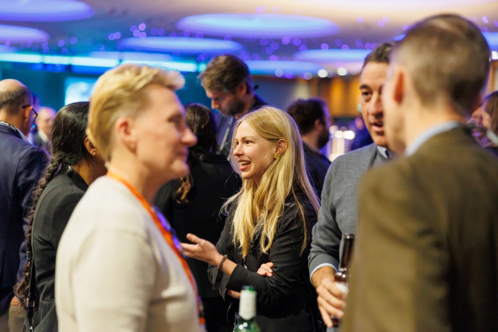 Woman smiling while talking with others chatting in foreground