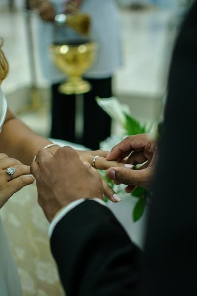 a bride and groom are putting on their wedding rings