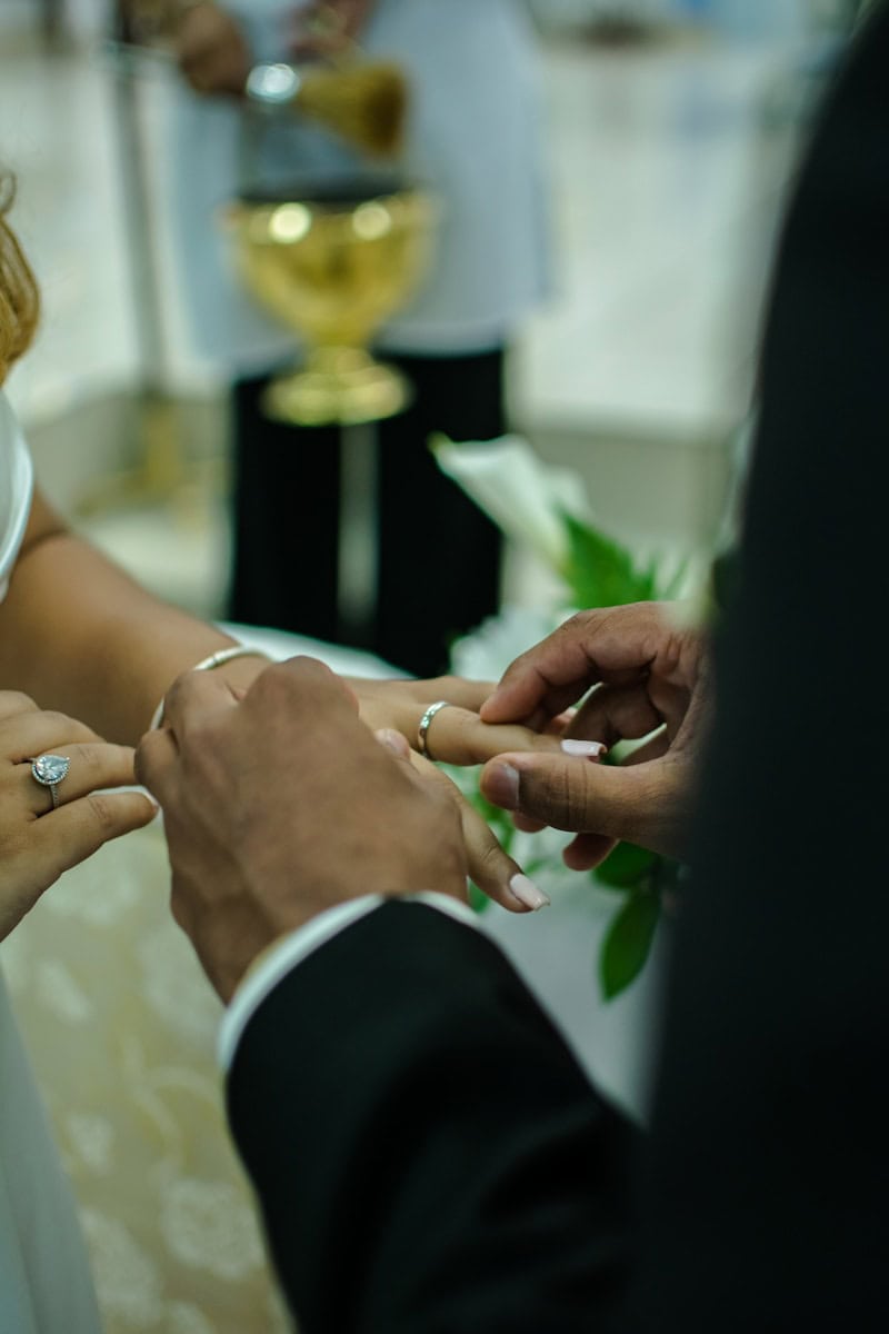 a bride and groom are putting on their wedding rings