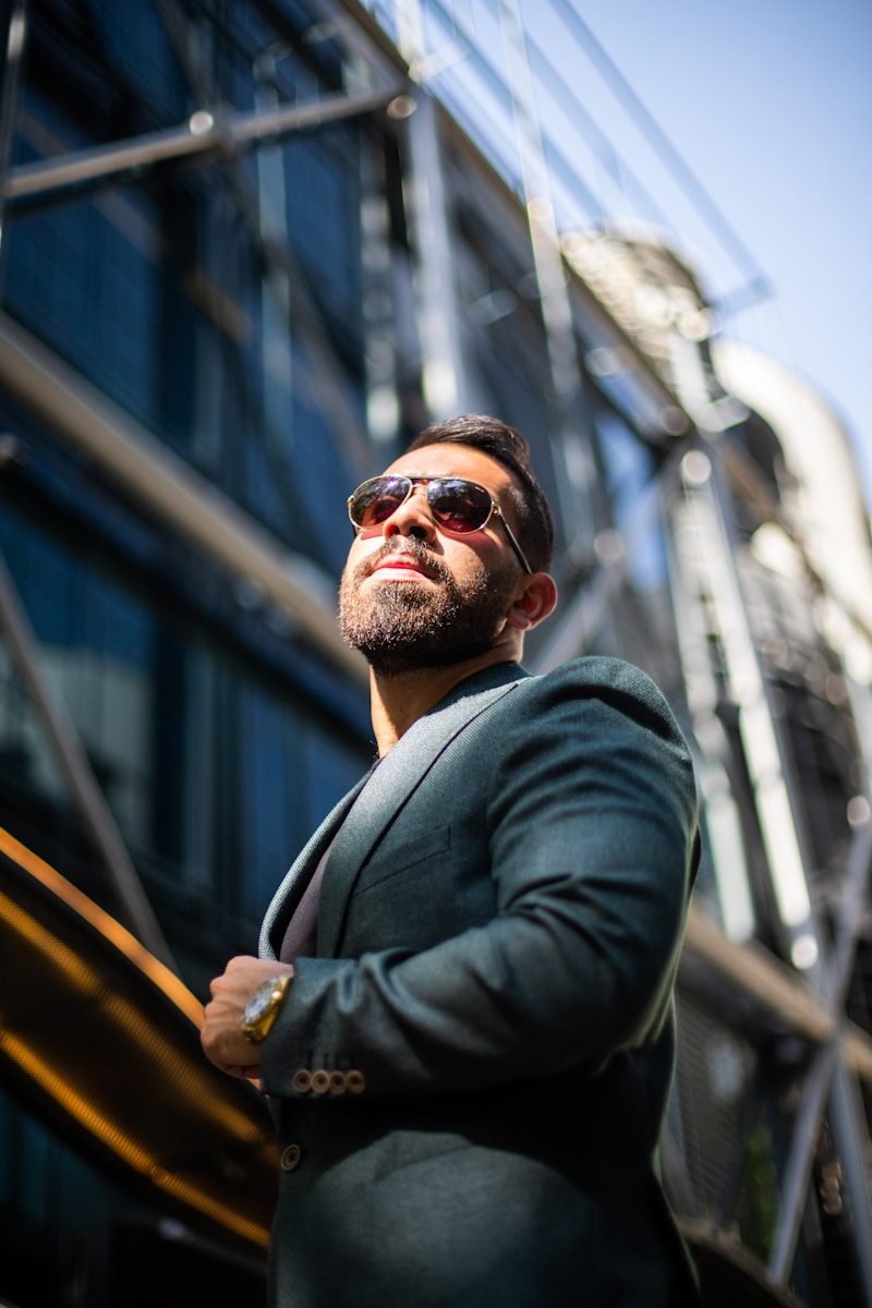 a man in a suit and sunglasses standing in front of a building