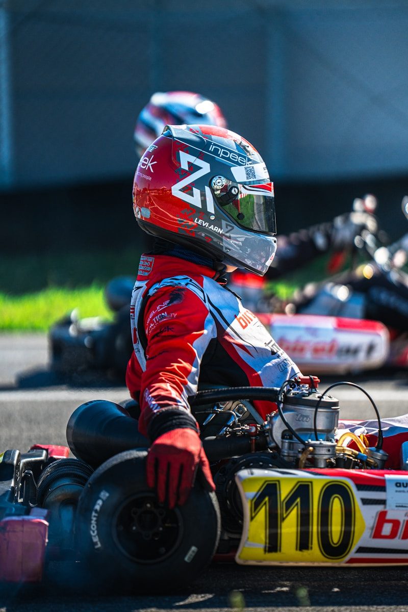 Go-kart racer in red suit and helmet waits